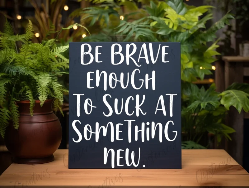 Be brave enough to suck at something new. Blue sign with white lettering.