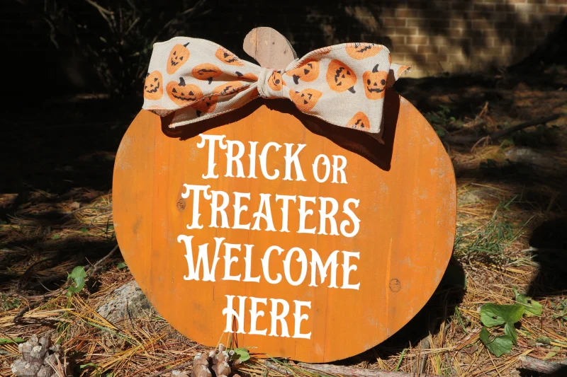 Trick or treaters welcome here. Orange wooden cedar pumpkin with accent bow.