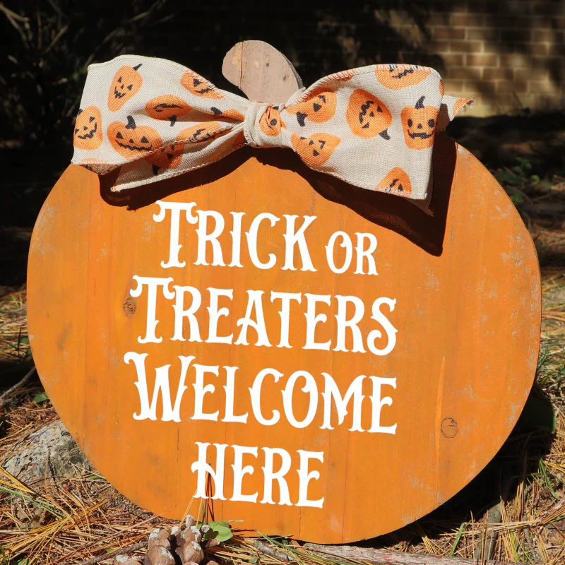 Trick or treaters welcome here. Orange wooden cedar pumpkin with accent bow.